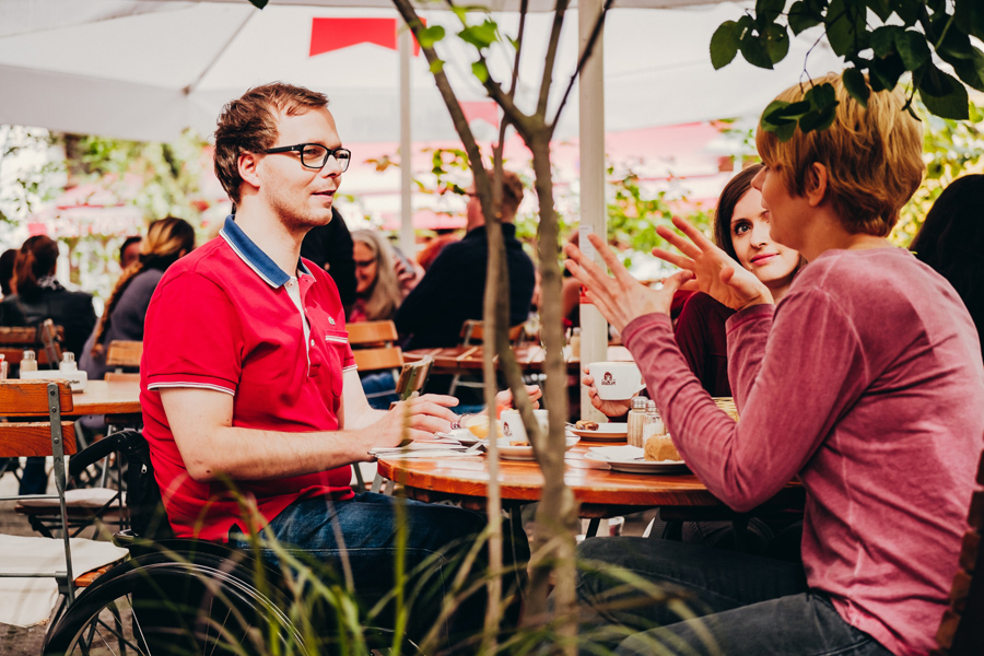 Rollstuhlfahrer mit zwei Frauen im Café © visitBerlin, Foto: Andi Weiland | Gesellschaftsbilder.de