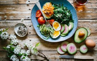 Symbolbild gesunde Ernährung: Teller auf Holztisch mit Gemüse, Ei, Samen und Rohkost, Photo by Brooke Lark on Unsplash