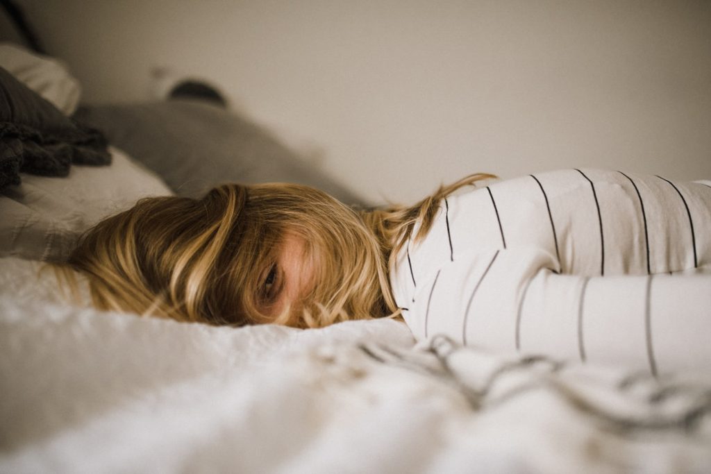 Symbolbild Schlaflosigkeit: Frau liegt wach im Bett, Credit: Kinga Cichewicz, Unsplash