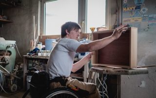 Junger Mann mit Rollstuhl arbeitet in Tischlerei, Bildnachweis: Andi Weiland | Gesellschaftsbilder.de