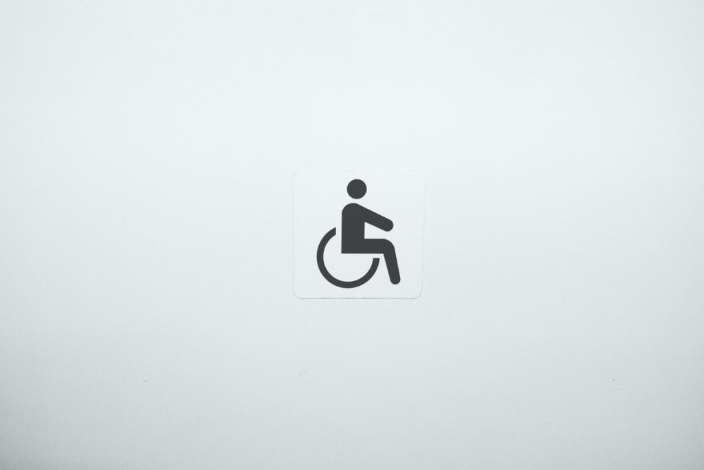 Rollstuhlsymbol auf beigem Hintergrund, Photo by Julius Carmine on Unsplash
