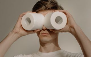 junger Mann sieht durch 2 Toilettenpapierrollen, Foto: cottonbro, Pexels